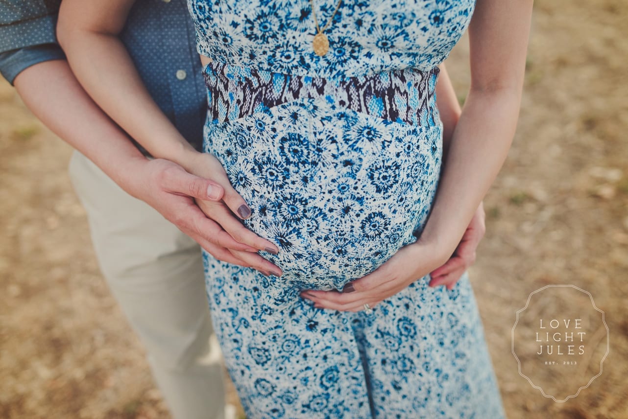 close-up-shot-with-mans-arms-around-pregnant-belly