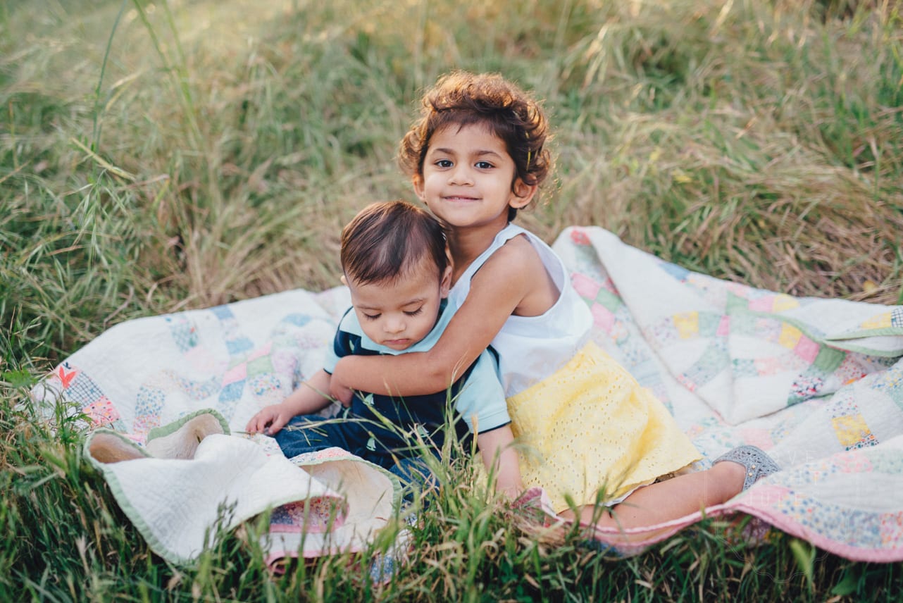 Brother-and-sister-on-quilt-for-outdoor-family-photos-in-sacramento
