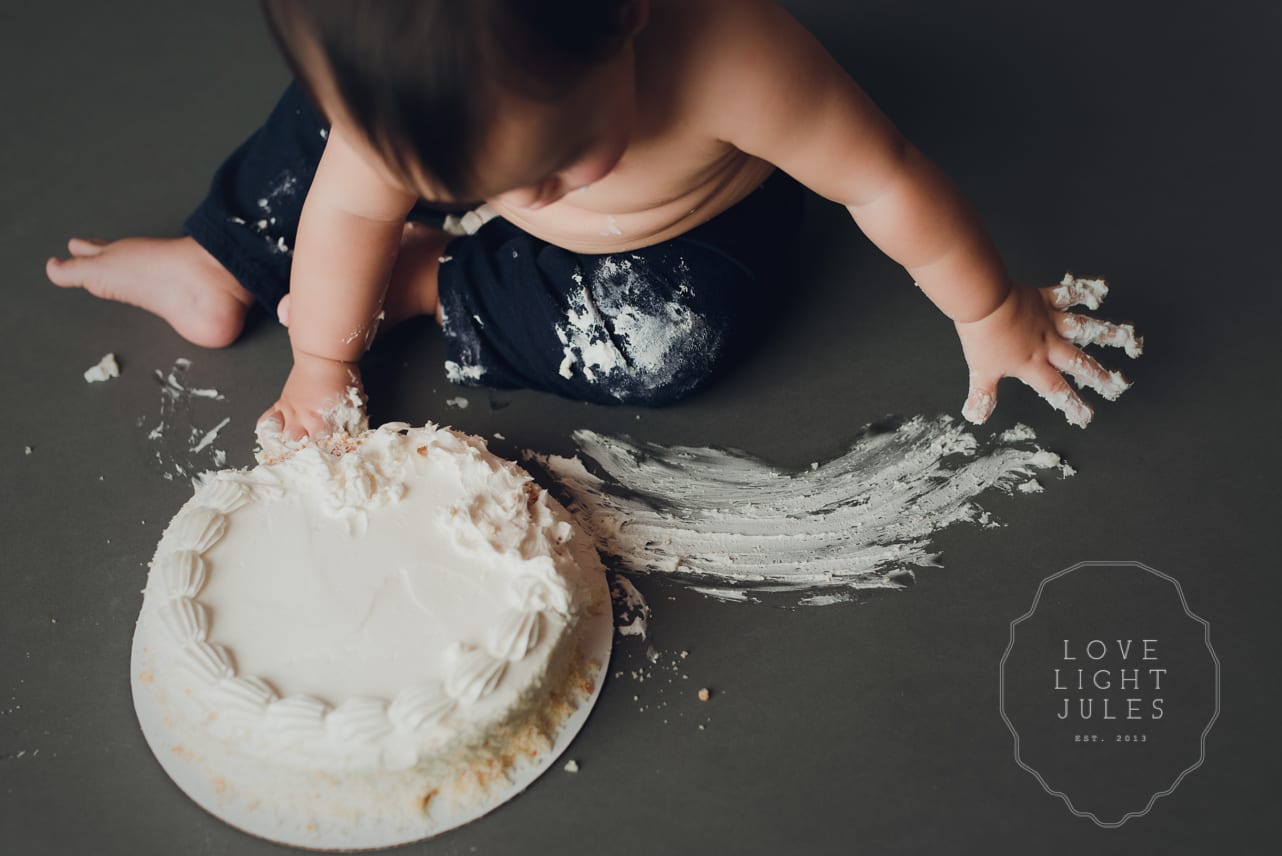 cake-smash-photo-session-with-white-frosting-on-grey-backdrop