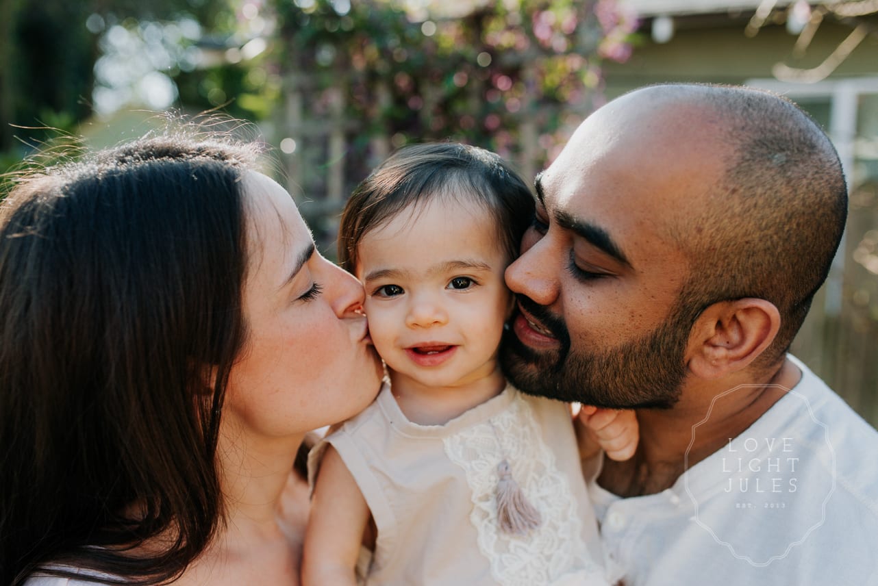 close-up-portrait-of-parents-kissing-baby
